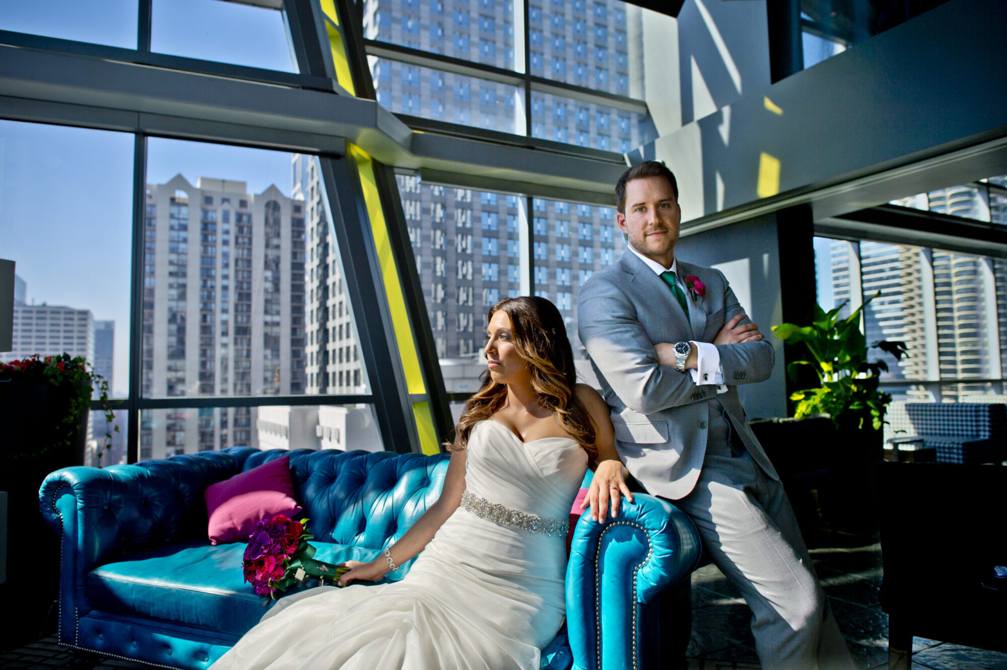 A bride and groom sitting together in an elegant hotel with a blue couch and gorgeous light and colors. Family and wedding photography in Pittsburgh.
