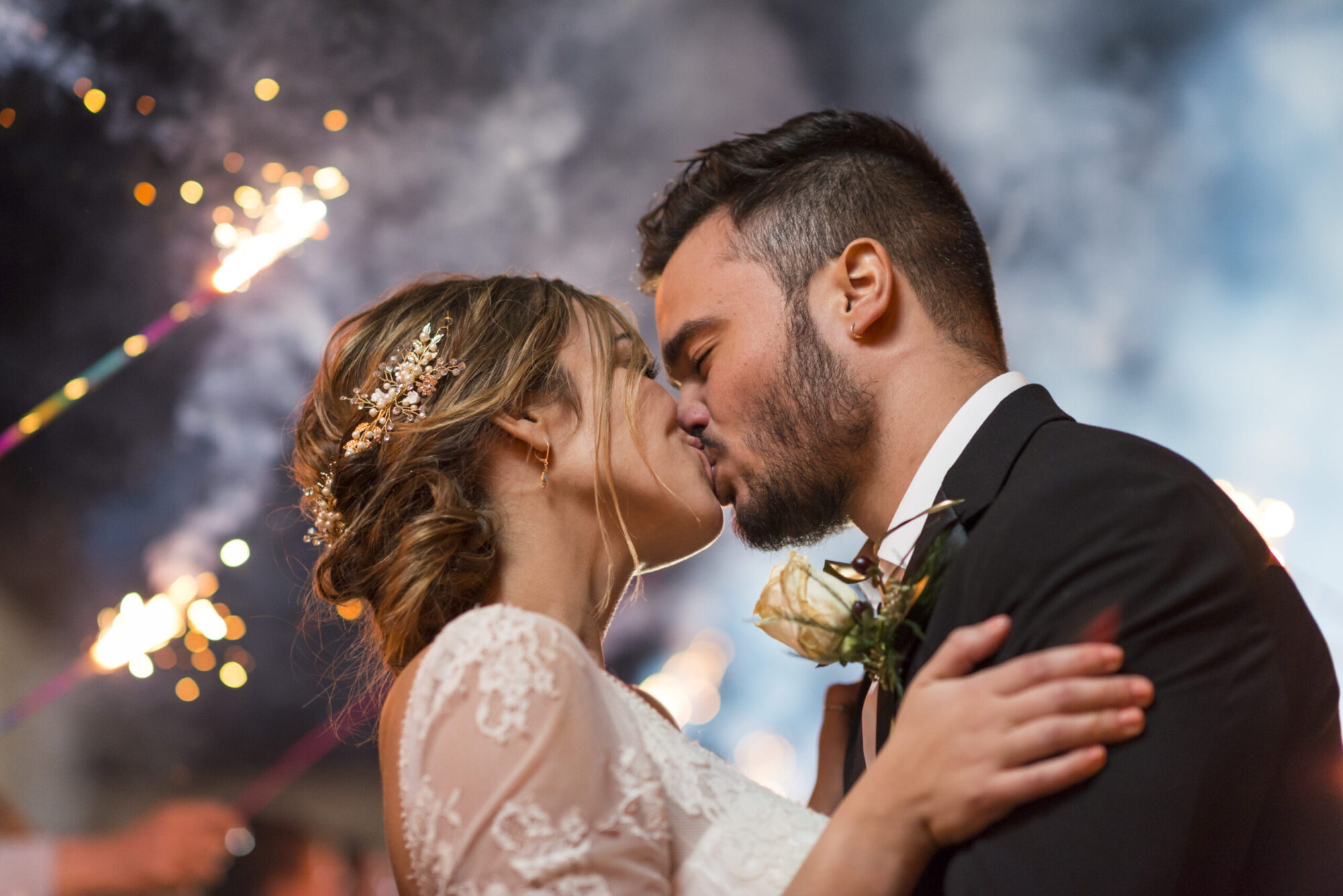 A beautiful bride kissing her groom at night with sparklers during their grand wedding exit. Family and wedding photography in Pittsburgh.
