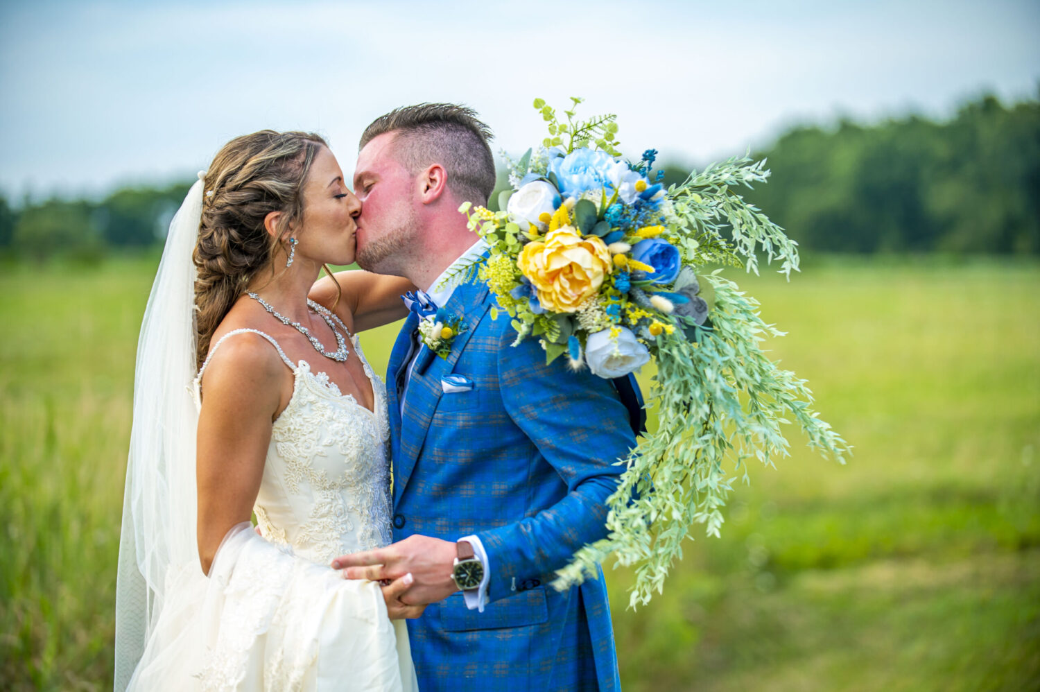 A bride holding a huge beautiful bouquet kissing her groom on their wedding day. Colorful. Family and wedding photography in Pittsburgh.